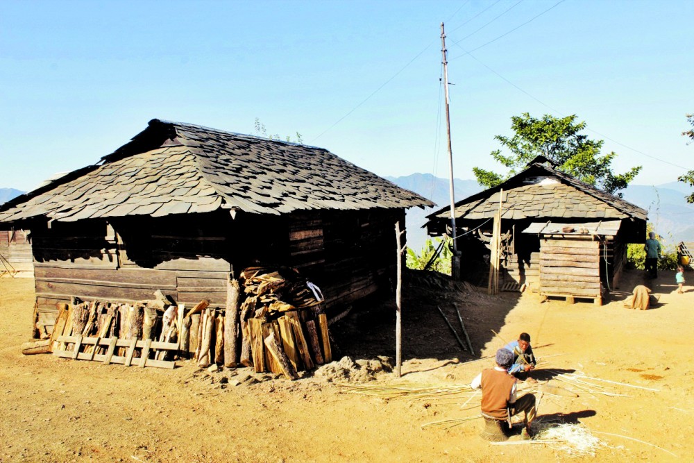 Two men making bamboo strips outside a slate roofed house in a village in Kiphire district. With the introduction of CGI sheet and other modern roofing system, the use of slate for roofing is fast disappearing. (Morung Photo)